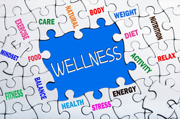 A puzzle with various words on each piece surrounding the word Wellness