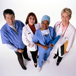 A group of four medical professionals smiling and looking up for a photo