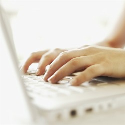 A photo of a set of hands typing on a laptop